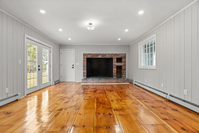 unfurnished living room with baseboard heating, a baseboard heating unit, ornamental molding, and light wood-style floors