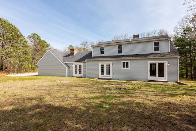 back of property featuring french doors, a lawn, and a chimney