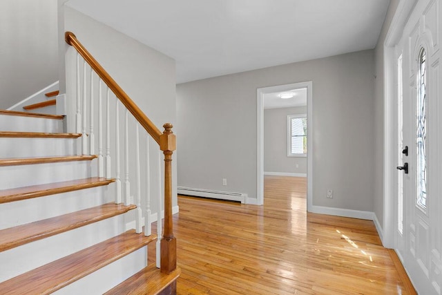 foyer featuring light wood-type flooring, baseboards, stairs, and a baseboard radiator