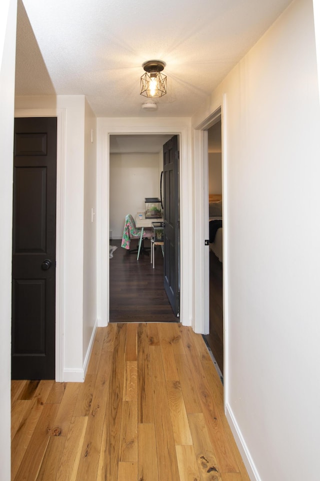 corridor featuring hardwood / wood-style flooring and a textured ceiling