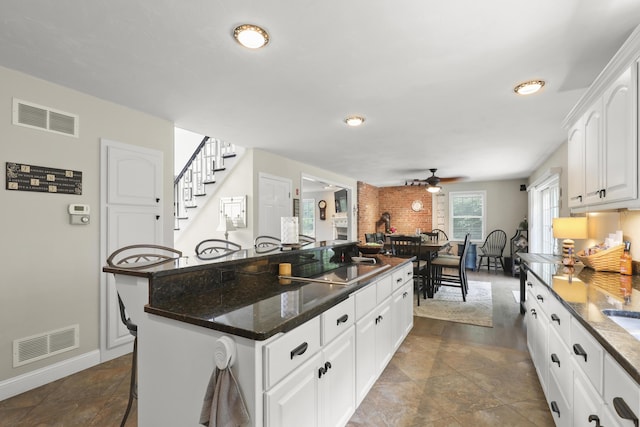 5 Lancaster Ln, Bourne, MA 02532 - kitchen featuring ceiling fan, a kitchen island, white cabinetry, baseboards, and dark stone countertops