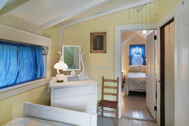 bedroom with light wood-type flooring, wood walls, and ornamental molding