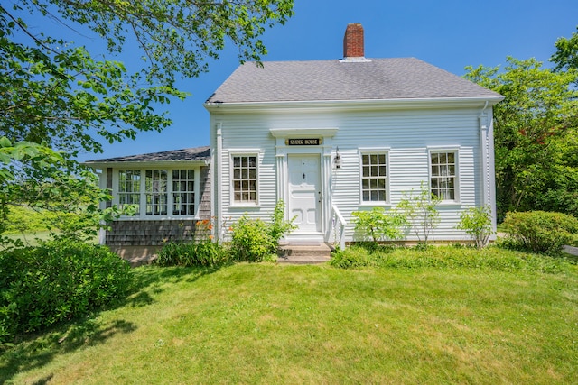 56 Wharf Ln, Yarmouth Port, MA 02675 - view of front facade with a chimney, a front yard, roof with shingles, and entry steps