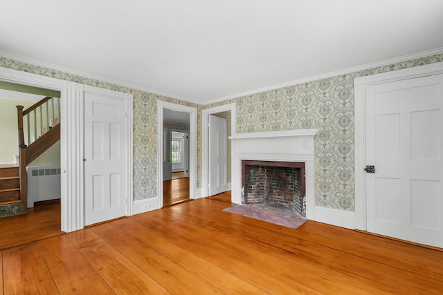 56 Wharf Ln, Yarmouth Port, MA 02675 - unfurnished living room with radiator heating unit, stairs, wallpapered walls, a fireplace with flush hearth, and light wood-type flooring