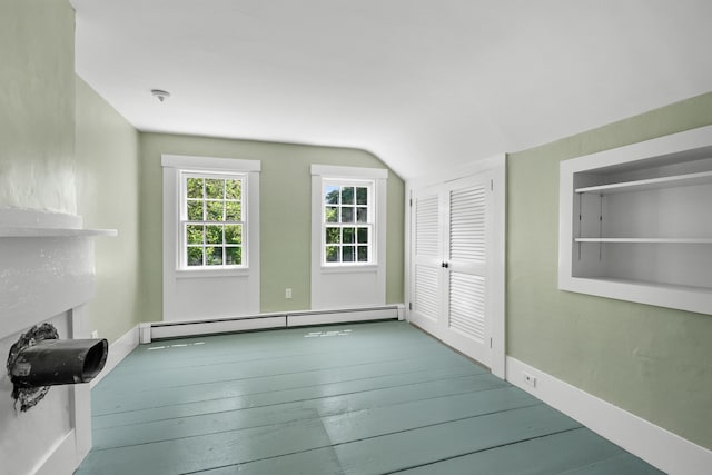56 Wharf Ln, Yarmouth Port, MA 02675 - unfurnished living room featuring a baseboard heating unit, vaulted ceiling, a fireplace, and wood finished floors