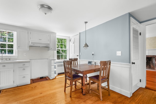 56 Wharf Ln, Yarmouth Port, MA 02675 - dining room featuring light wood finished floors, radiator heating unit, and a wainscoted wall