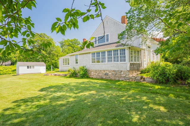 56 Wharf Ln, Yarmouth Port, MA 02675 - rear view of property featuring a chimney, an outdoor structure, and a lawn