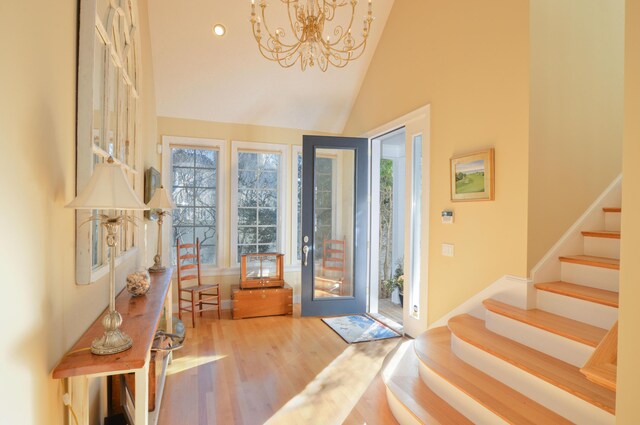foyer featuring stairs, a notable chandelier, high vaulted ceiling, wood finished floors, and recessed lighting
