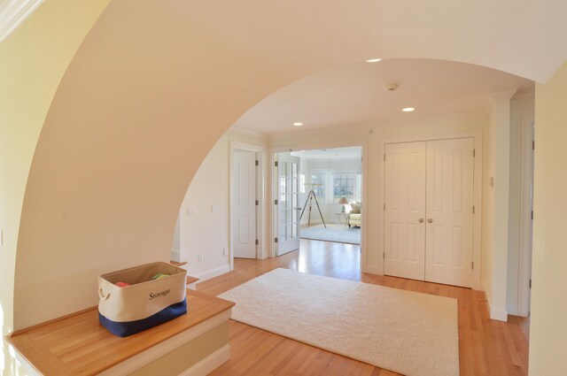 hall with crown molding, recessed lighting, baseboards, arched walkways, and light wood-style flooring
