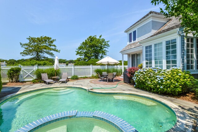 view of swimming pool with a pool with connected hot tub, a gate, fence, and a patio