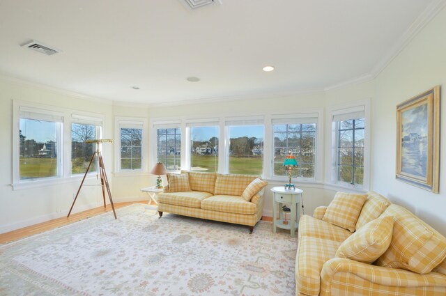 living area featuring ornamental molding, visible vents, a healthy amount of sunlight, and wood finished floors