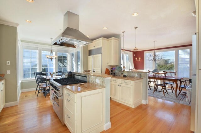 kitchen with island range hood, a kitchen island, a notable chandelier, and stainless steel range