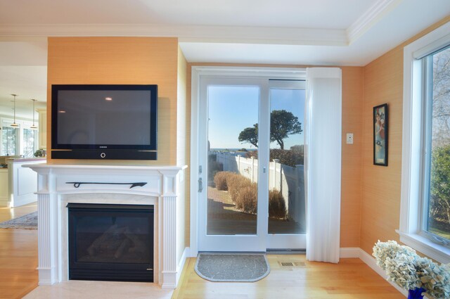 living area featuring ornamental molding, baseboards, visible vents, a fireplace, and wood finished floors