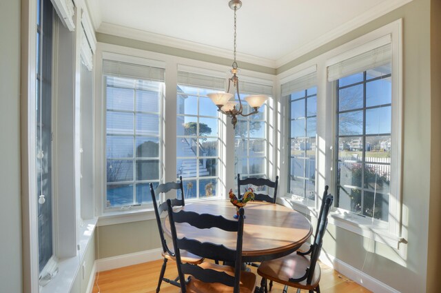 dining space featuring baseboards, a chandelier, crown molding, and light wood finished floors