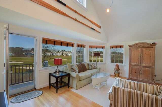 living room featuring baseboards, high vaulted ceiling, and light wood-style floors