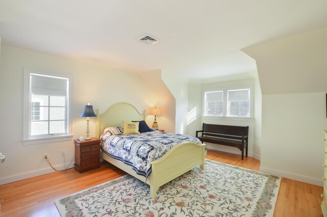 bedroom with visible vents, baseboards, and wood finished floors