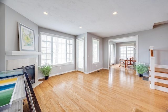 living area featuring baseboards, light wood-style floors, a tile fireplace, and recessed lighting