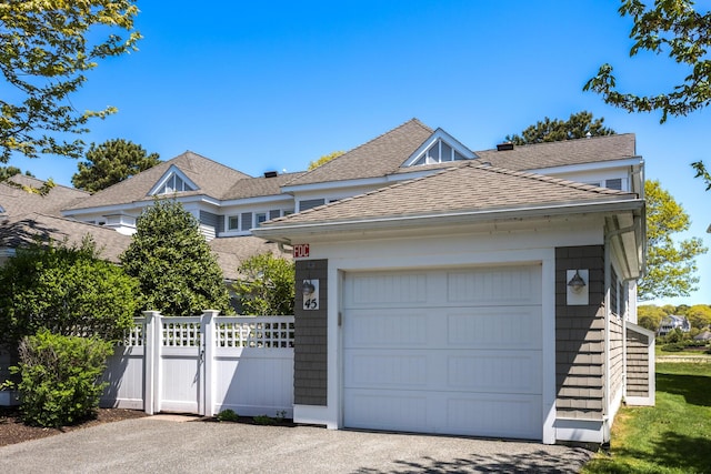 view of front of property featuring roof with shingles, fence, and a gate
