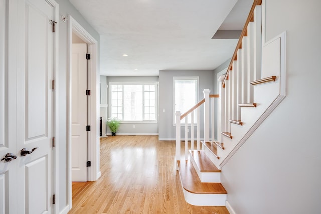 entryway featuring light wood-style flooring, stairs, and baseboards