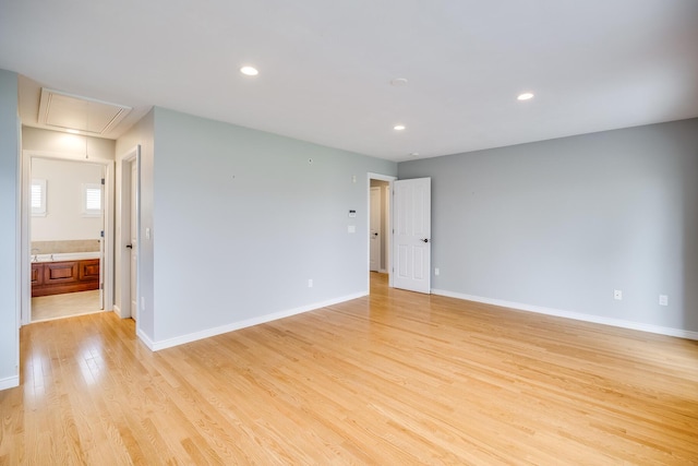 spare room featuring attic access, light wood finished floors, recessed lighting, and baseboards