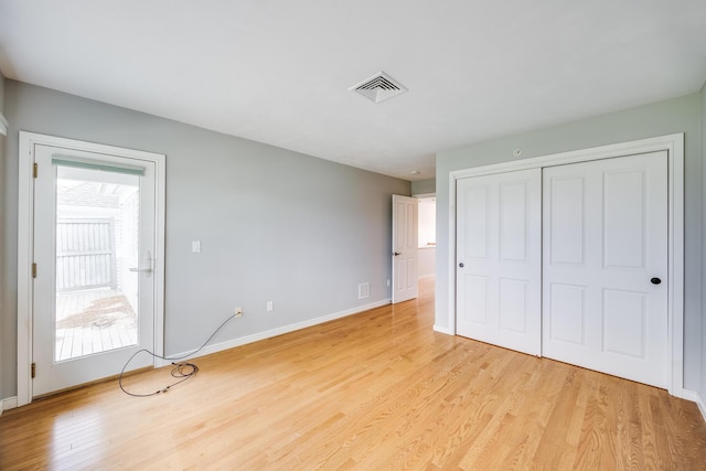 unfurnished bedroom with multiple windows, light wood-style floors, and baseboards