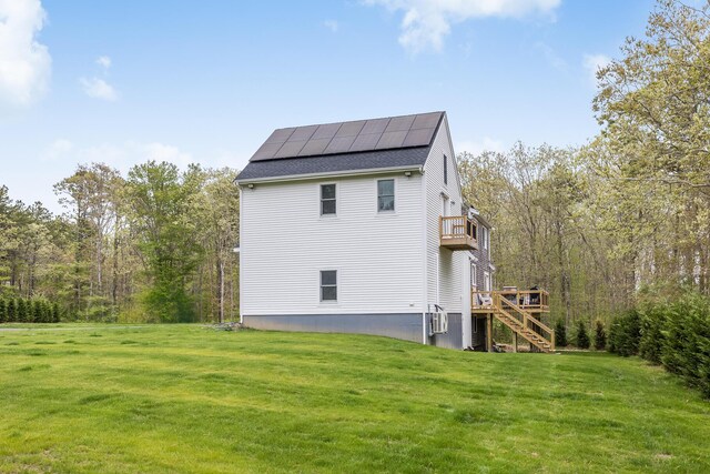 115 Kiahs Way E, Sandwich, MA 02537 - back of property featuring a lawn, stairway, solar panels, roof with shingles, and a balcony