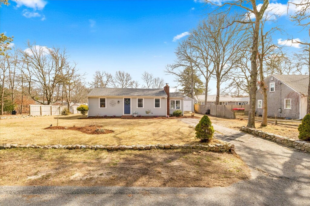 view of front of property featuring a chimney, fence, and aphalt driveway
