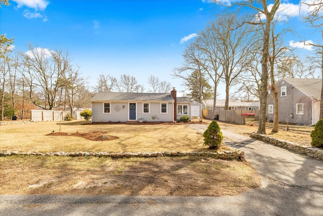 view of front of property featuring a chimney, fence, and aphalt driveway