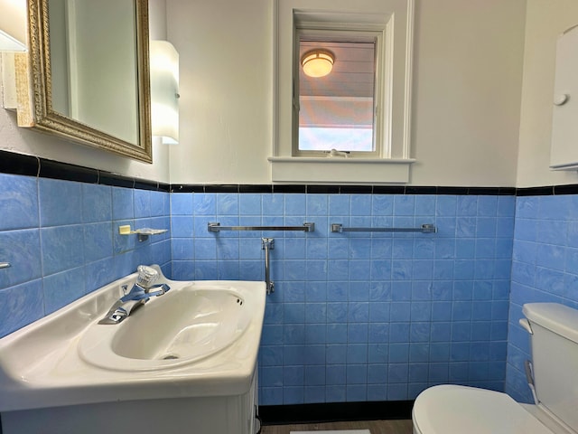 bathroom featuring sink, toilet, and tile walls