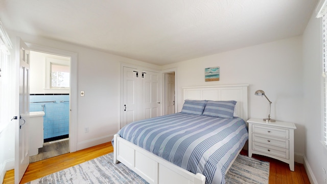 bedroom featuring ensuite bath and light wood-type flooring