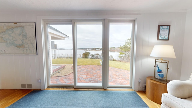 entryway with light wood-type flooring, a water view, and crown molding