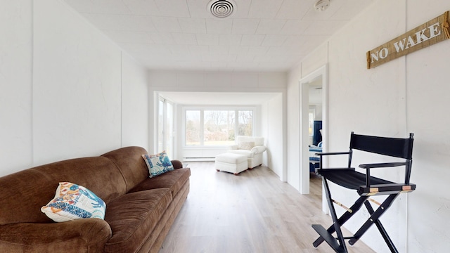 living room with a baseboard heating unit and light hardwood / wood-style floors