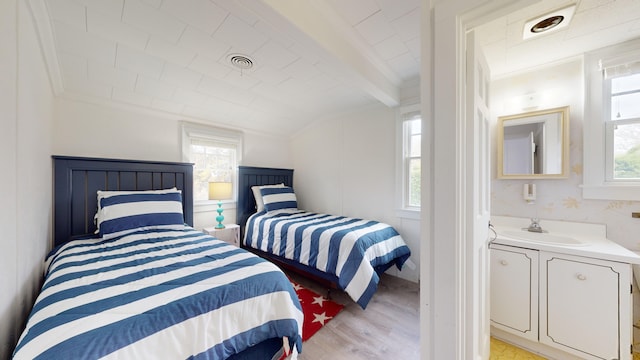 bedroom with sink, light wood-type flooring, and ornamental molding