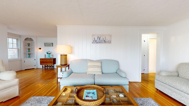 living room with built in features, hardwood / wood-style floors, a textured ceiling, and crown molding