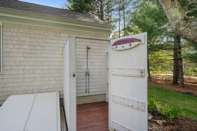 exterior view of roof with shingles, a downspout, gutters, and a bulkhead entry