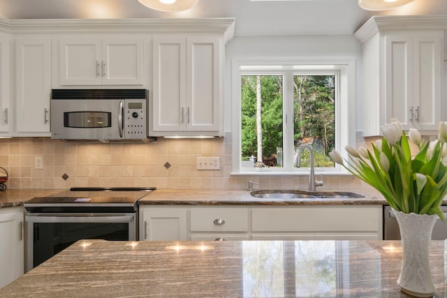 kitchen with appliances with stainless steel finishes, white cabinets, backsplash, and a sink