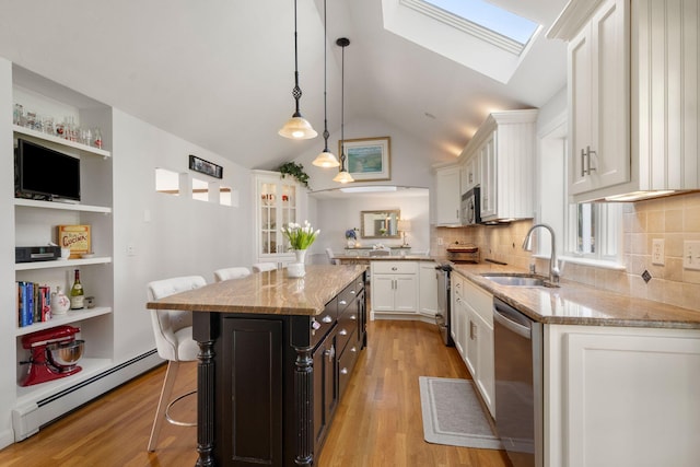 kitchen with a sink, a baseboard radiator, stainless steel appliances, white cabinets, and light stone counters