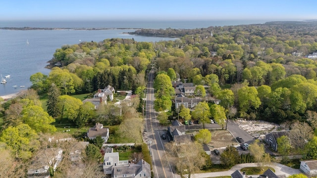 aerial view of property and surrounding area with a nearby body of water and a heavily wooded area