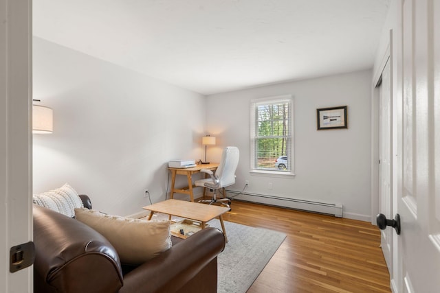 living area with baseboard heating, wood finished floors, and baseboards