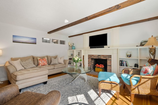 living room with wood finished floors, beamed ceiling, and a fireplace