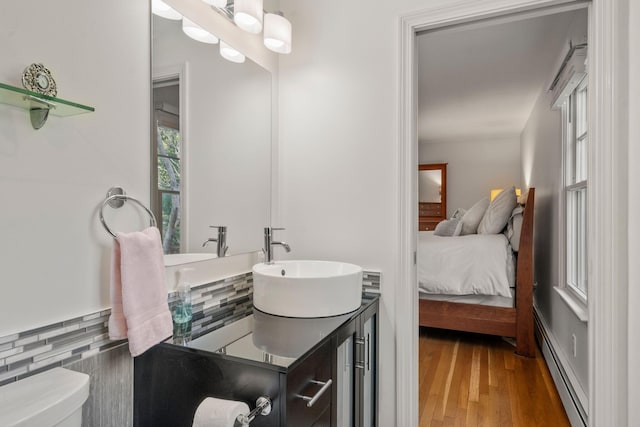 bathroom featuring baseboard heating, connected bathroom, toilet, wood finished floors, and vanity