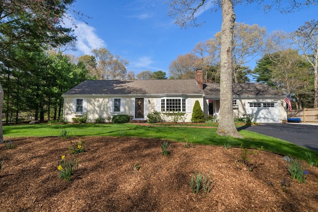 single story home featuring a chimney, an attached garage, asphalt driveway, and a front yard