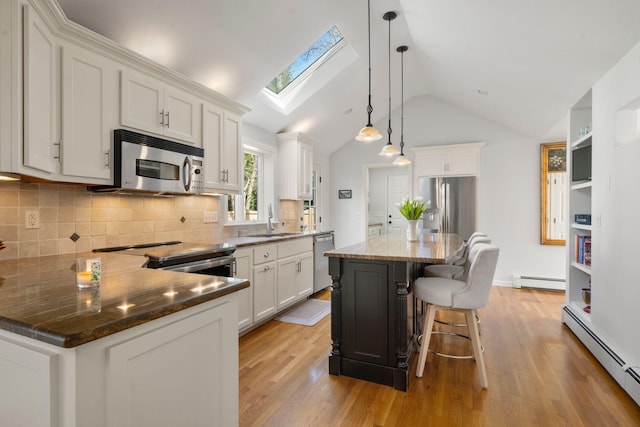 kitchen with stainless steel appliances, a baseboard radiator, a sink, a skylight, and light wood-style flooring