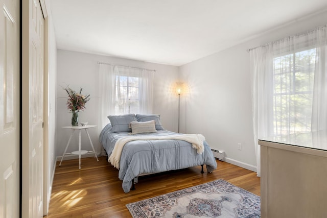 bedroom featuring baseboard heating, wood finished floors, and baseboards
