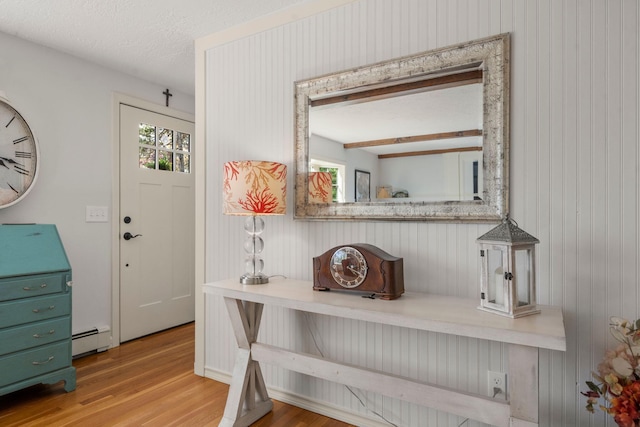 detailed view of a baseboard heating unit, wood finished floors, wooden walls, and a textured ceiling