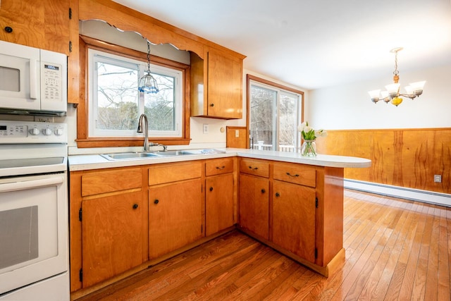 kitchen with a baseboard radiator, light countertops, a sink, white appliances, and a peninsula