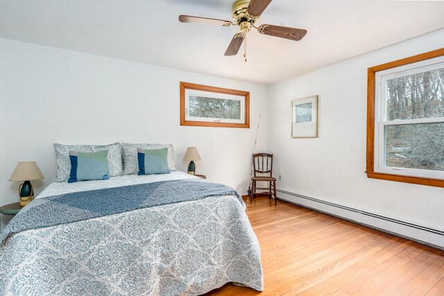 bedroom with ceiling fan, a baseboard radiator, and light wood-style floors