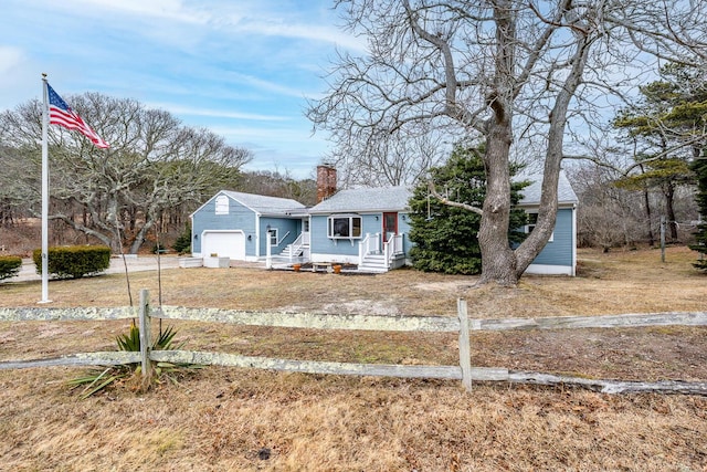 view of front of house featuring a garage, driveway, fence, and a chimney