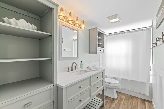 full bathroom featuring vanity, hardwood / wood-style flooring, shower / bath combination with curtain, and toilet