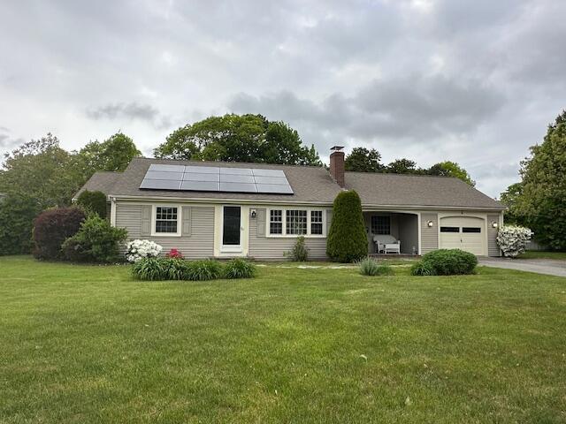 2 Stiles Rd, South Yarmouth, MA 02664 - ranch-style house with a garage, asphalt driveway, a front lawn, roof mounted solar panels, and a chimney